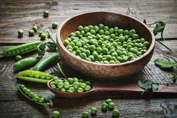 Delicious ripe green peas lying on a wooden table.