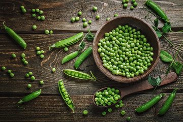 Delicious ripe green peas lying on a wooden table.