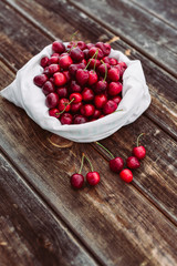 Fresh cherries in white bag on wood