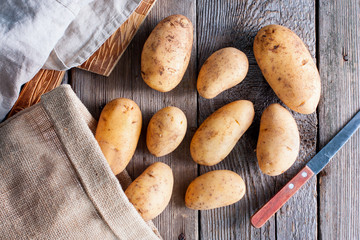 Young raw fresh potatoes on a wooden table, top view