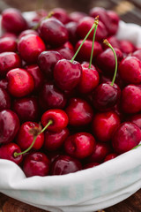 Fresh cherries in white bag on wood