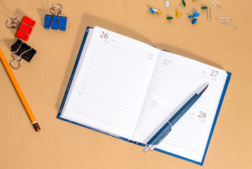 Notepad, pen, pencil,  clips on a brown background