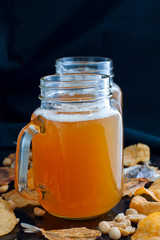 Lager beer and snacks on stone table. Nuts, chips.