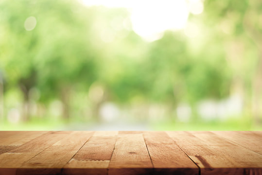 Wood table top on blur green background of trees in the park