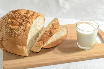 Homemade bread, sliced on a wooden board with milk