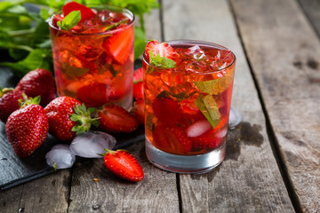 Strawberry mojito and ingredients on rustic background