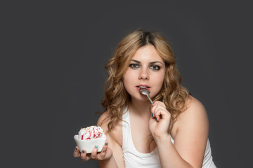 Attractive long haired young woman has a spoon in her open mouth and is looking at the camera.