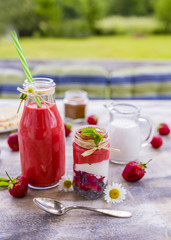 Delicious strawberry smoothie on the wooden table in the garden.