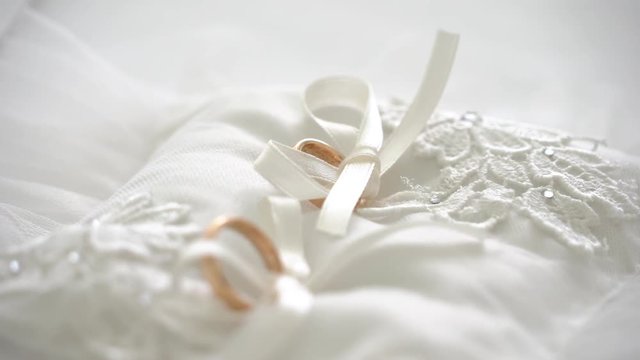 Wedding rings in a white pillow with ribbons 