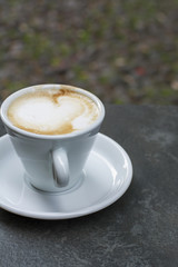 White cup of strong coffee is on the grey table