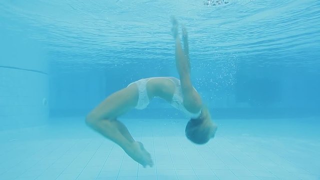 Attractive woman performing acrobatic tricks underwater
