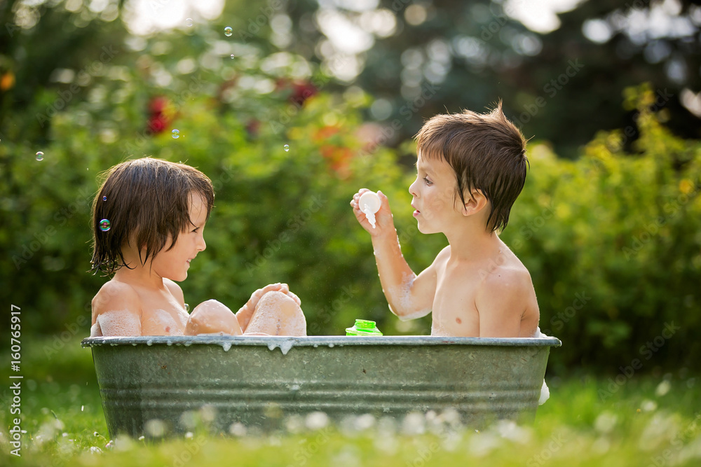 Poster Two children, boy brothers, having a bath outdoors, making soap bubbles