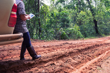 Stressed woman calling for help on cell phone with tablet on dirt road - car breakdown