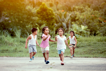 Asian children having fun to run and play together in the field in vintage color tone