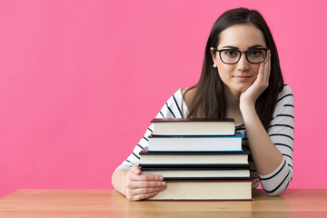 Happy smiling attractive female student sitting at her desk with textbooks