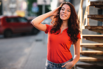 Summer outdoor porttrait of young pretty girl posing at sunset in city