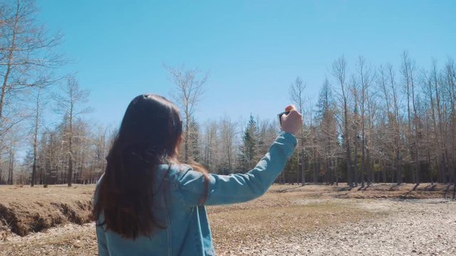 Girl makes selfie in a sunny forest. 4k.