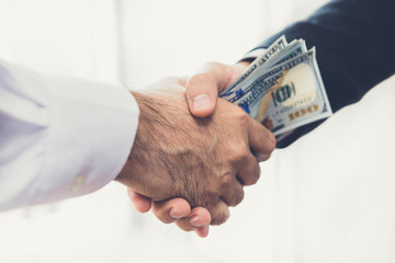 Businessmen making handshake with money in hands