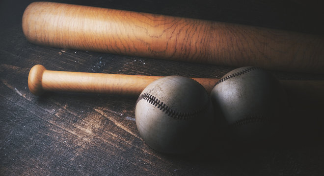 Two baseballs and bats on wooden desk