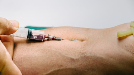 Doctor  hands medical gloves using needle syringe drawing blood sample from patient arm in hospital.