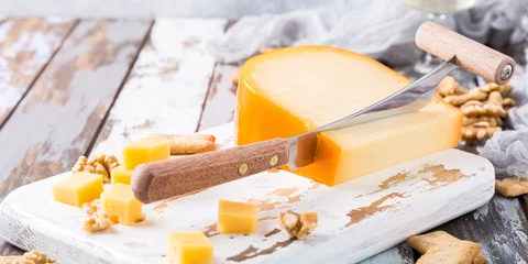 Foto op Aluminium Delicious dutch gouda cheese with cheese blocks, crackers, walnuts and special knife on old wooden table. © Iryna Melnyk