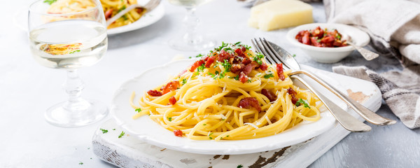 Italian pasta spaghetti Carbonara with fried bacon, parmesan cheese and parsley on white plate. Restaurant food concept.