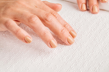 Finger read braille alphabet in white paper.