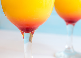 Two cocktails with orange juice and tequila on a blue background. Summer drink with a straw in a glass