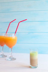 Two cocktails with orange juice and tequila on a blue background. Summer drink with a straw in a glass