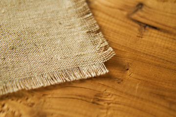 The napkin from sackcloth on a brown wooden background.