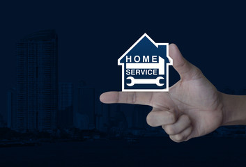 Hammer and wrench with house icon on finger over modern city tower, Home service concept