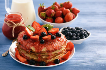 Stack of homemade pancakes with strawberry mousse and berries.