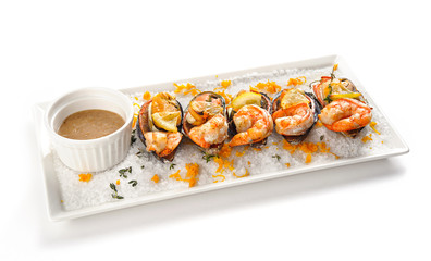 Seafood. Shellfish mussels baked with shrimp or king prawns with lemon and tomatoes on salt dish with sauce. Isolated on white background.