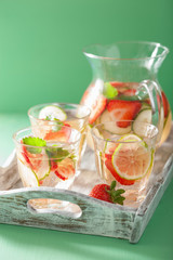 refreshing summer drink with strawberry cucumber lime in jar and glasses