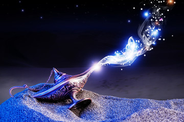  magical aladdin lamp with smoke coming out in a night resting on the dunes of a desert. magical...