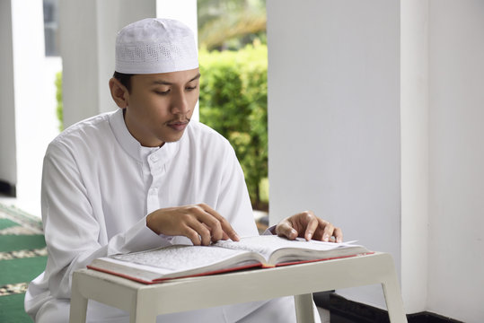 Religion asian muslim man with cap reading holy book Koran