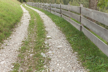 Wooden fence long a secondary mountain white street in Val di Funes