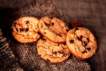 Chocolate cookies on dark  napkin on wooden table. Chocolate chip cookies on brown coffee color cloth, macro, top view