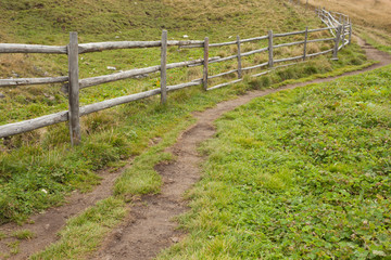 Fototapeta na wymiar Wooden fence long a path in Val di Funes
