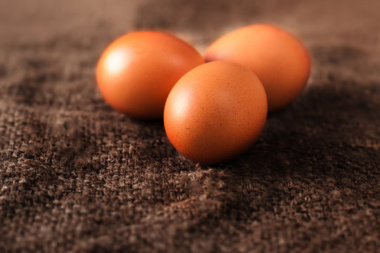  Heap of fresh brown Eggs on wooden  background closeup image in dark orange colors