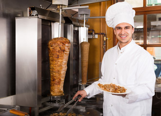 Smiling arabian cook posing near meat for kebab