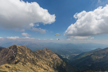 paragliding in the Swiss mountains with blue sky and clouds