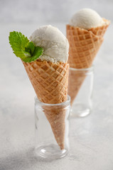 Vanilla ice cream in waffle cone on grey concrete background, selective focus