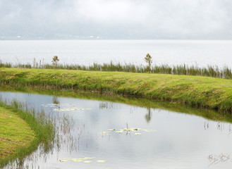 A green grass elevation around a small artificial island at Bratan, Bedugul, Bali, Indonesia, November 2016