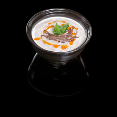Mushroom cream soup on a black background with reflection