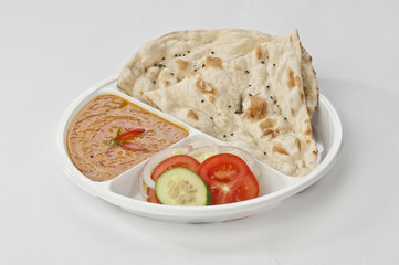 Butter naan with dal tadka and fresh vegetable on white disposable plate