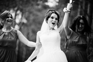Fototapeta na wymiar Fantastic bride with awesome bridesmaids having fun in the forest on a wedding day. Black and white photo.