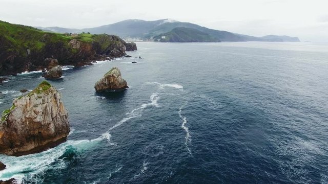 Amazing aerial drone footage of vibrant green shore line with cliffs, flyng over mesmerizing natural national park ocean waters and waves crushing on rocks, currents of cold streams