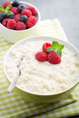 Oatmeal porridge in bowl with berries raspberries and blackberries.