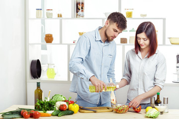 Loving happy couple preparing healthy salad of fresh vegetables in kitchen